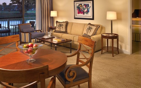 living room with a couch and coffee table, round table with three chairs and balcony 