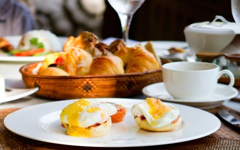 eggs benedict on a plate, croissants and coffee 