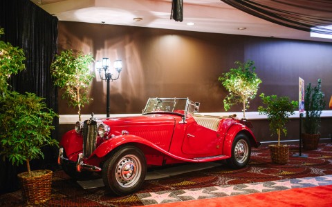 an antique red car on display in a room 